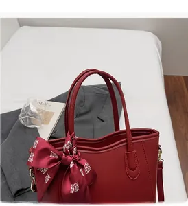 Dettaglio della borsa rossa da sposa con sciarpa di seta decorata sul manico solido