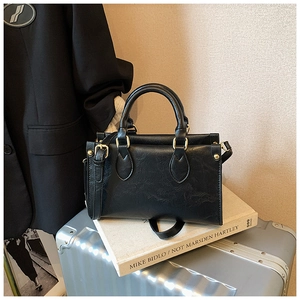 Close-up of black retro textured leather handbag with gold metal hardware on luggage