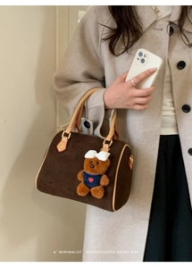 Detail of vintage brown suede boston bag with cute teddy bear charm accessory