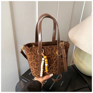 Dettaglio della borsa tote scamosciata leopardata con manici in pelle e ciondolo