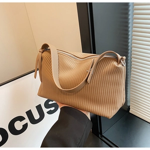 Detailed view of the vertical pleat texture and zipper on the khaki tote bag