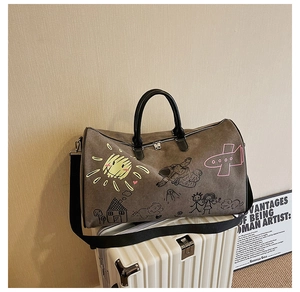 Detail of a large brown canvas duffel bag with creative hand-drawn graffiti on a suitcase