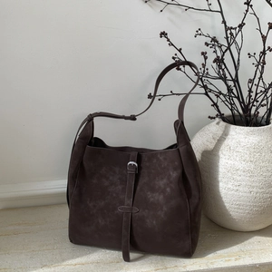 Detail of vintage dark brown suede oversized hobo bag with buckled leather strap