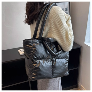 Side view of a large black quilted puffer tote bag with thick padded handles for winter