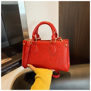 Detail of red pebbled leather small square bag with gold hardware and dual handles
