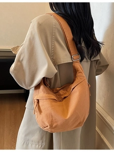 Sac bandoulière minimaliste en toile orange-brun porté avec un trench d'automne élégant