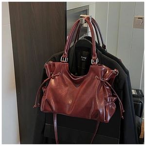Detailed view of dark red oil-wax leather tote with drawstring folds and silver hardware