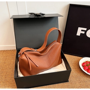 Close-up of brown pleated leather tote bag inside a luxury gift box with golden zipper detail