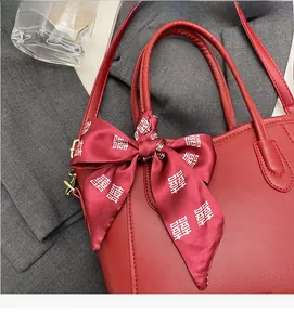 Dettaglio borsa tote in pelle rossa opaca con fiocco in seta Doppia Felicità e fibbia d'oro