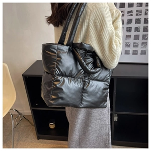 Detail of black quilted down puffer bag with glossy finish and thick dual handles