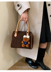 Detail of dark brown suede Boston bag featuring soft handles and a cute teddy bear charm