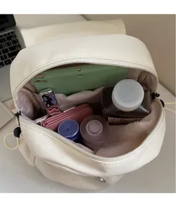 Detailed view of the spacious main compartment of the cream canvas backpack with essentials