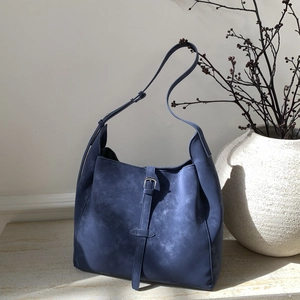 Detailed close-up of retro blue suede bucket bag texture and adjustable strap buckle