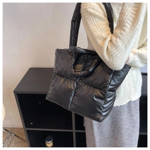 Detail of a black quilted down tote bag with high-gloss nylon and thick shoulder strap