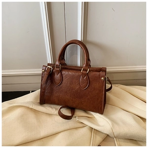 Detail view of the brown retro square bag featuring golden studs and durable hardware