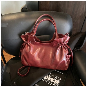 Detailed view of dark red oil-wax leather tote bag with drawstring texture on black chair