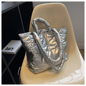 Close-up of silver quilted down tote bag with metallic finish on a cream chair