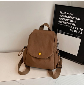 Detail of dark brown canvas backpack with a decorative yellow button and drawstring side pocket
