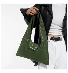 Détail du sac à bandoulière en daim vert foncé avec œillets métalliques sur l'anse