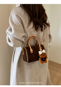 Detail view of retro suede Boston bag with plush bear charm and leather handle