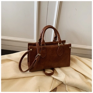 Detail showing high-quality brown PU leather texture and gold hardware on the handbag