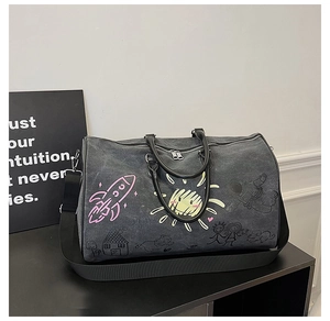 Close-up of graffiti-style grey canvas travel bag with pink rocket and sun patterns
