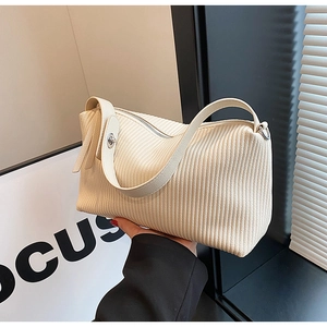 Close-up of cream textured tote bag with pleated fabric detail and metal twist lock