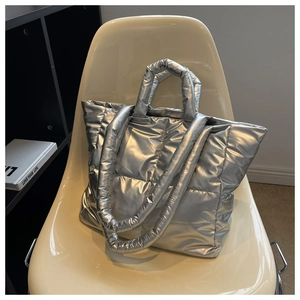 Detail of silver metallic quilted tote bag with padded handles on a vintage chair