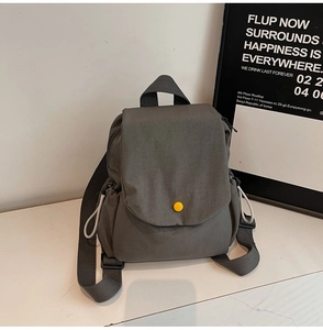 Detail of dark grey canvas backpack featuring a yellow round snap and drawstring side