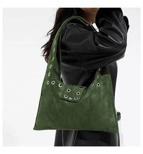 Détail du sac à bandoulière en daim vert foncé avec de grands œillets métalliques argentés