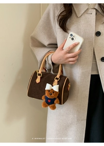 Detail of retro dark brown matte handbag with plush bear charm and leather handles