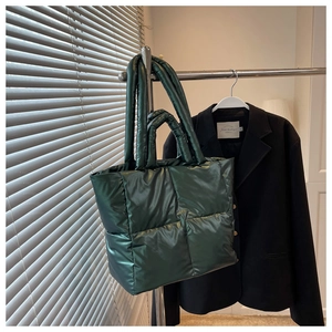 Detail of dark green quilted puffer tote bag with metallic gloss and double handles