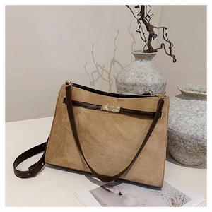 Close-up of vintage brown suede tote bag featuring a golden metal twist lock and leather strap