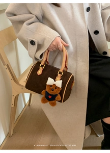 Close-up of brown suede Boston bag with a cute bear charm and retro vibe text
