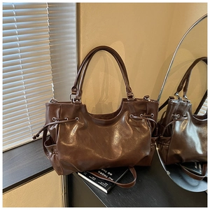 Detail of dark brown glossy tote bag with drawstring texture and side pocket details
