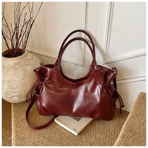 Macro detail of glossy burgundy oil wax leather tote bag with drawstring side and soft texture