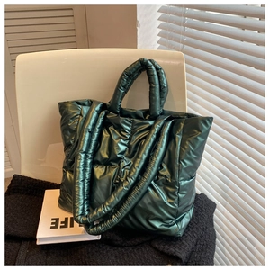 Detailed view of dark green quilted puffer tote bag with metallic glossy finish on white chair