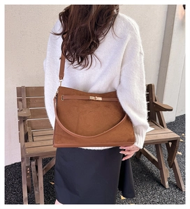 Detail of vintage brown suede shoulder bag featuring gold twist-lock and elegant strap