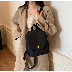 Close-up of lightweight black canvas backpack with a yellow snap button on flap