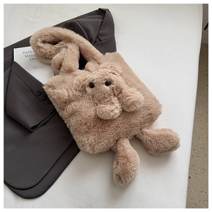 Detail of light brown plush tote bag featuring 3D cartoon bear design on suit background