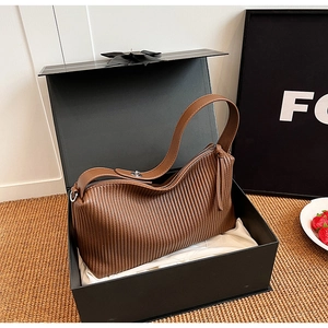 Detailed view of a brown pleated leather tote bag featuring a tassel zipper in a gift box