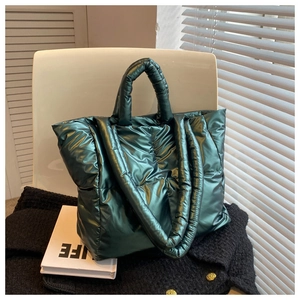 Macro detail of dark green quilted tote bag with metallic finish on a white chair