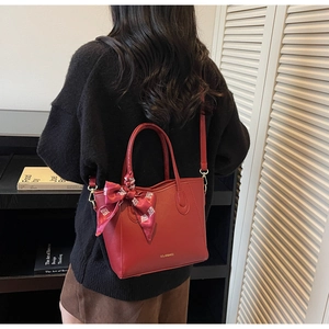 Detailansicht der roten Ledertasche mit goldenem Logo und Seidenschleife im Chinas-Stil