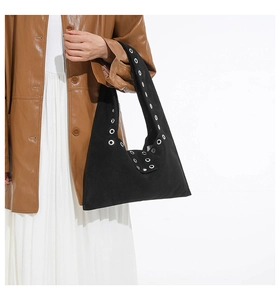 Détail du grand sac noir à bandoulière avec des œillets argentés sur la sangle