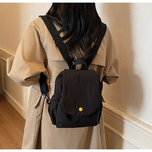 Detailed back view of a minimalist black canvas backpack with a bright yellow button