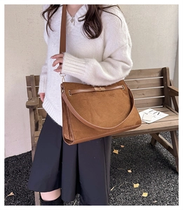 Detail view of large dark brown suede tote bag with metal turn-lock and contrast leather strap