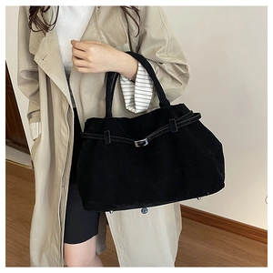 Detalle del bolso tote de ante negro con hebilla metálica y remaches de protección