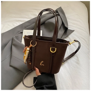 Dettaglio borsa a secchiello vintage in pelle scamosciata con perline e logo dorato