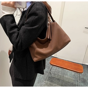 Detail of vintage brown leather tote bag showing unique vertical pleated texture on a model