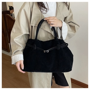 Detalle de un bolso tote grande de ante negro con hebilla plateada y pies metálicos
